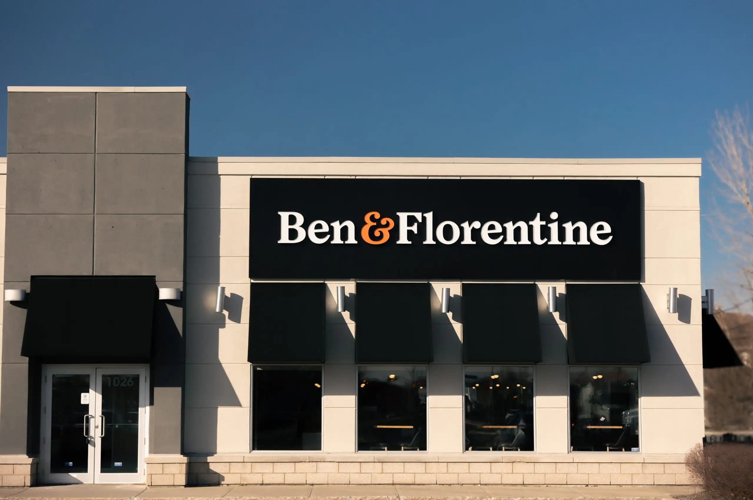 Ben & Florentine restaurant exterior with black awnings and clear blue sky.