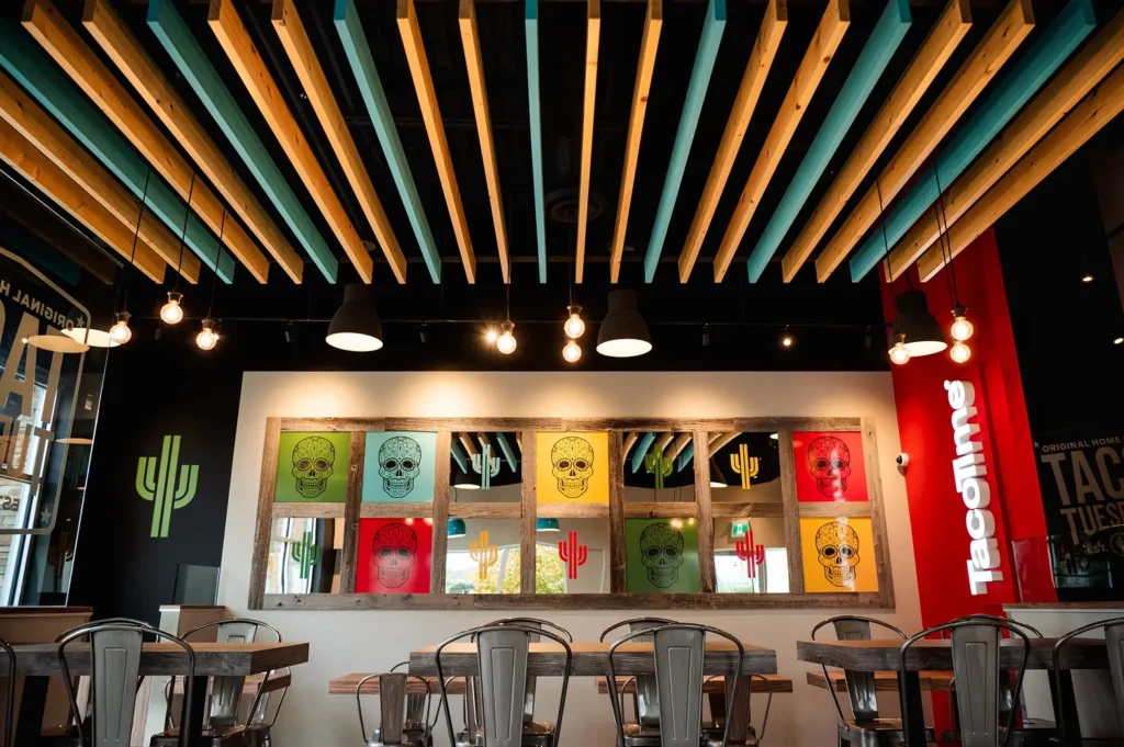 Interior of a TacoTime restaurant with colorful sugar skull artwork, modern furniture, and the TacoTime logo | TacoTime Franchise FAQs: Support, Costs, and What You'll Need to Know Blog