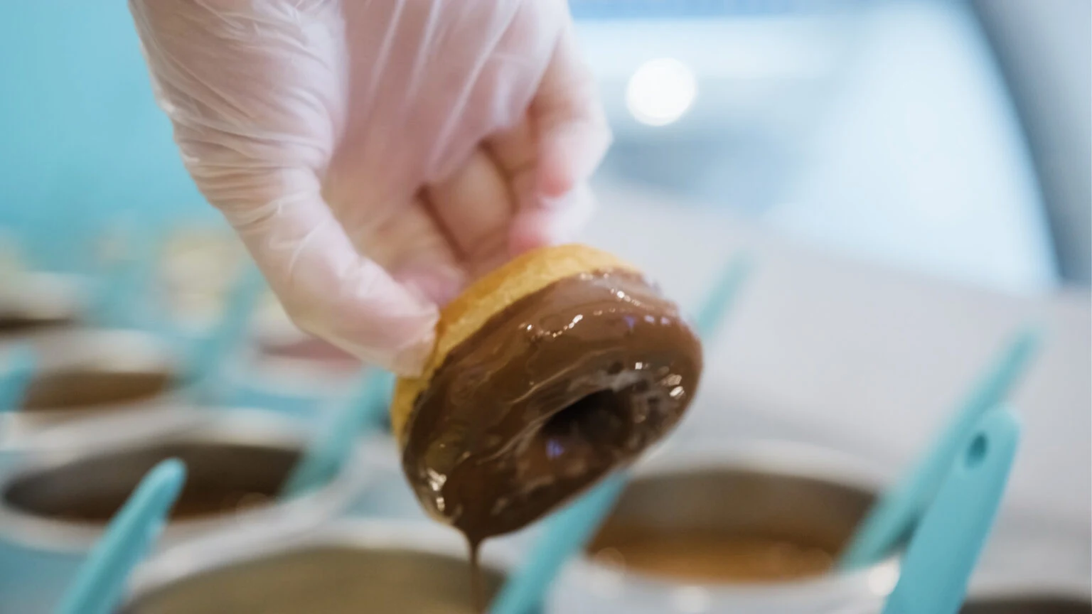 La Diperie franchise team member dipping a donut in premium chocolate.