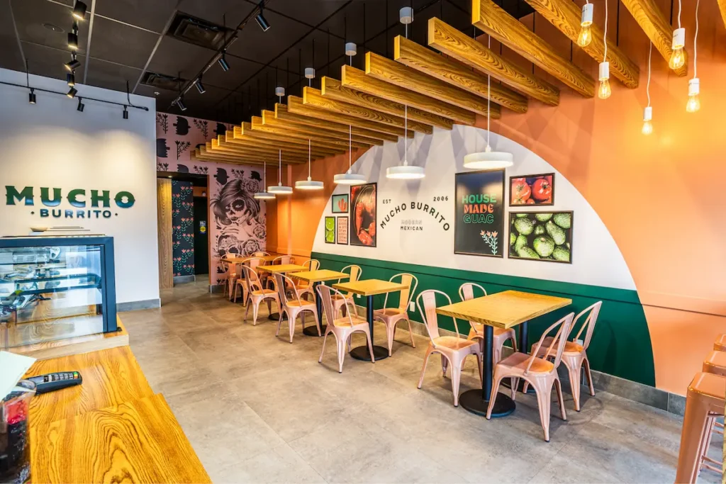 Mucho Burrito fast-casual franchise interior featuring modern décor, comfortable seating, and vibrant branding elements.