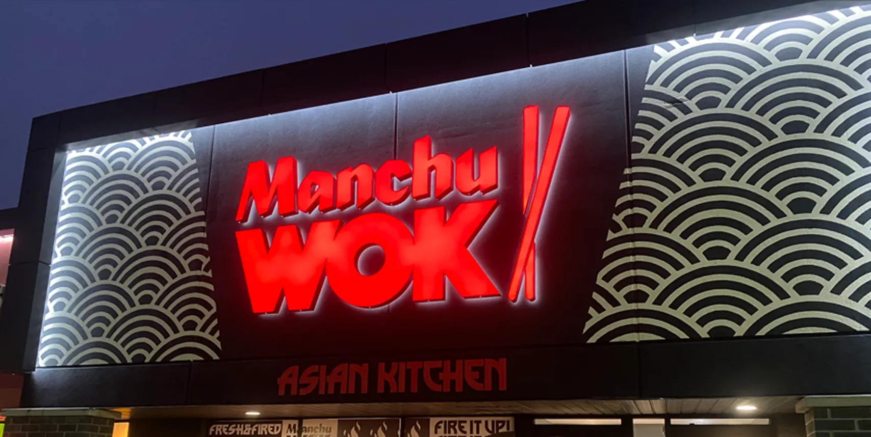 Illuminated Manchu WOK storefront at night with bold red signage and modern wave design, reflecting the dynamic identity of Canada’s leading Chinese WOK franchise. | MTY Group Franchising
