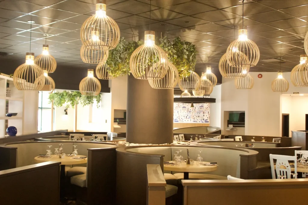 Elegant dining room with sculptured wood pendant lights, curved booth seating, and warm Mediterranean ambiance.