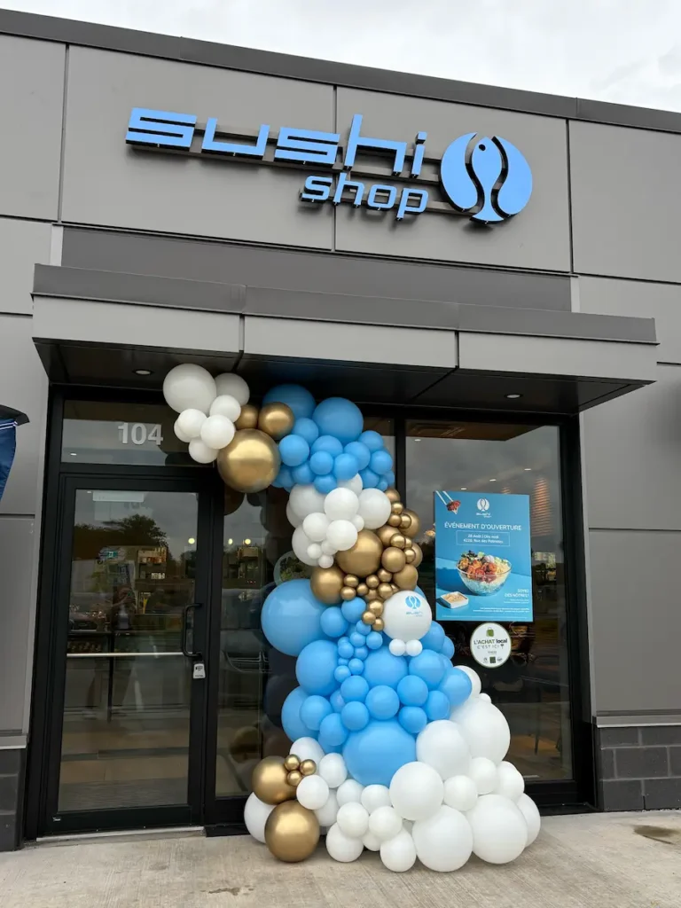 Sushi Shop storefront with blue, white, and gold balloon garland at the entrance.