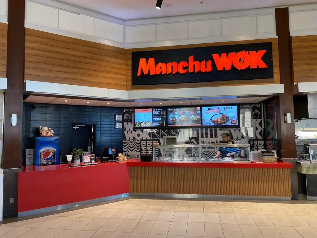 Manchu WOK food court counter in a shopping mall with red signage and digital menu boards.